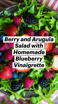 a bowl filled with berries and greens on top of a striped table cloth next to a fork