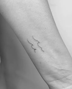 a woman's arm with a small wave tattoo on it