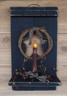 a lighted candle sits in front of a wooden star with a wreath and bow around it