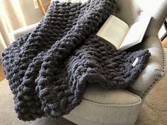 an open book is laying on a chair with a crocheted blanket draped over it