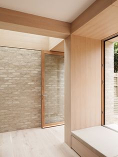 an empty room with a bench in front of a brick wall and sliding glass doors