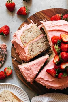 slices of strawberry cake with frosting and strawberries on the plate next to it