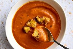 a white bowl filled with tomato soup and croutons