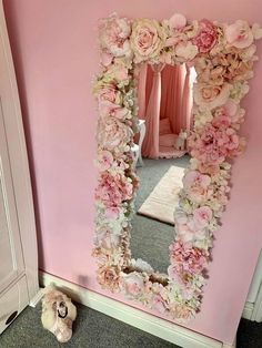 there is a mirror with flowers on it and a stuffed animal in front of it