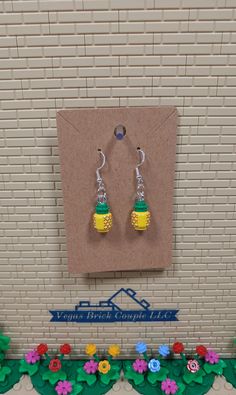 a pair of yellow and green earrings sitting on top of a table next to flowers