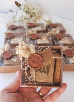 a person holding a box with some items in it and flowers on the table behind them