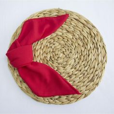 a straw hat with a red bow on it sitting on top of a white table