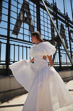 a woman in a white dress is walking down the street