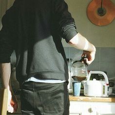 a man standing in the kitchen pouring something into a blender