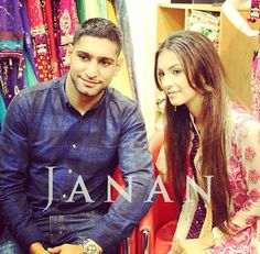 a man and woman sitting next to each other in front of some clothes on display