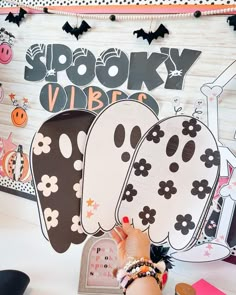 a person is holding up some paper plates in front of a halloween themed wall with the words spooky vibes on it