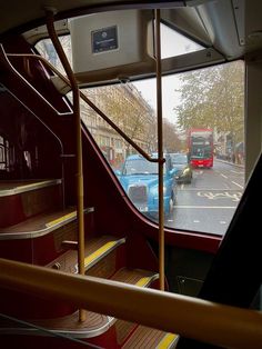 an open bus door with stairs and cars on the street in front of it as seen from inside