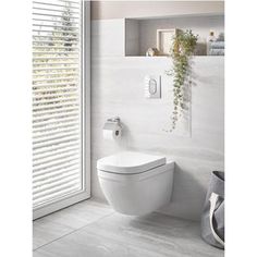 a white toilet sitting in a bathroom next to a window with blinds on the outside