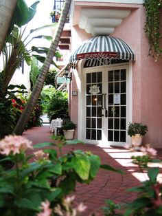 a pink building with a striped awning and potted plants