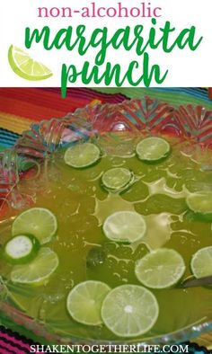 a bowl filled with liquid and limes on top of a colorful table cloth next to a