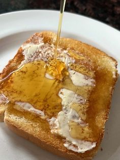 a piece of bread with butter and honey on it is being drizzled