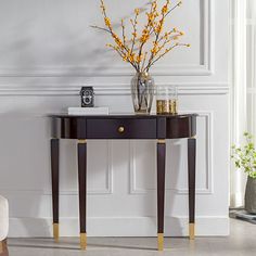 a vase with flowers on top of a table in front of a wall and a chair