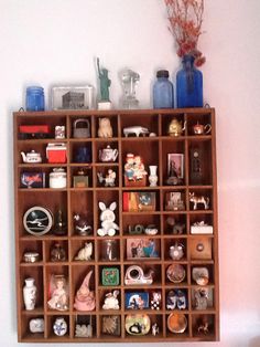 a wooden shelf filled with lots of different items next to a wall mounted vase on top of it