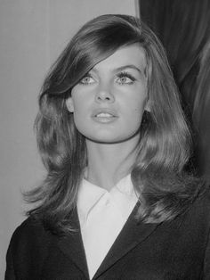 a black and white photo of a woman with long hair wearing a blazer jacket