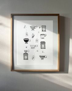 a black and white drawing of coffee cups in a wooden frame hanging on the wall