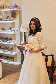 a woman in a wedding dress standing next to a shelf with shoes and flowers on it