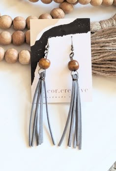 a pair of earrings with wooden beads and tassels on top of a table