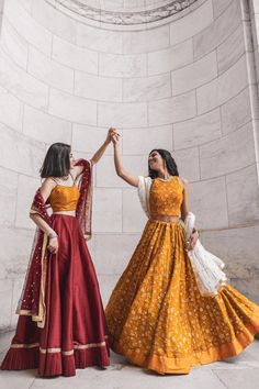 two women dressed in yellow and red are holding hands