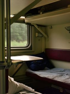 there is a bunk bed in the corner of this train car that has two windows