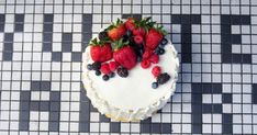 a white cake topped with berries on top of a black and white checkered table