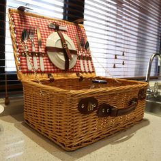 a wicker picnic basket with utensils in it on a kitchen countertop