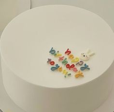 a white cake topped with lots of colorful letters