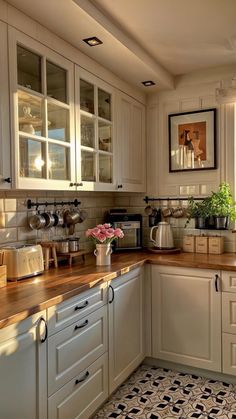 a kitchen with white cabinets and wooden counter tops next to a potted plant on the counter