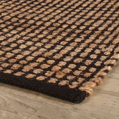 a brown and black area rug on the floor with wood floors in the background at an angle