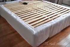 a bed frame made out of wooden slats on top of a hard wood floor