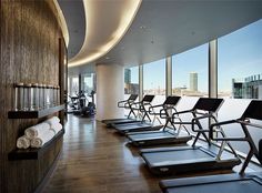 there are many treadmills lined up in the gym with windows overlooking the city