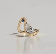 a yellow gold ring with a pear shaped diamond and two blue diamonds on the side