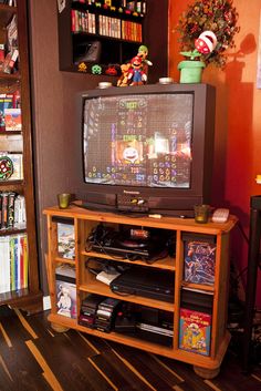 a television sitting on top of a wooden stand in front of a bookshelf