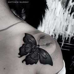 a black and white photo of a butterfly on the back of a woman's shoulder