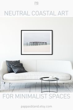 a white couch sitting in front of a painting on the wall next to a coffee table