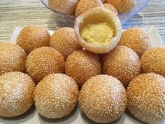 several buns on a white plate with a bowl of mustard in the middle and another container full of them