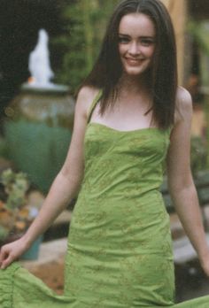 a young woman in a green dress posing for a photo with her hands on her hips