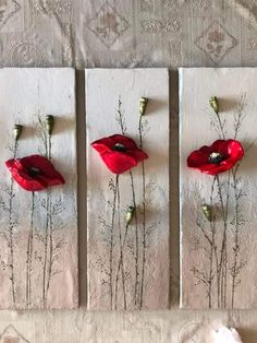 three red flowers are displayed on white canvases with silver stems and leaves in the center