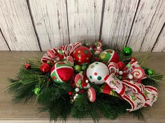 an arrangement of christmas ornaments and decorations on a wooden surface with white boards in the background