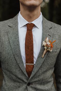 a man wearing a suit and tie with a boutonniere on his lapel