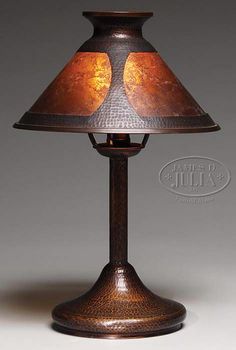 a lamp that is sitting on top of a white tablecloth with a brown shade