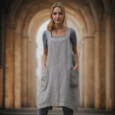 a woman standing in front of an archway wearing a gray dress and grey tights