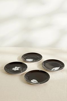 four black plates with white designs on them