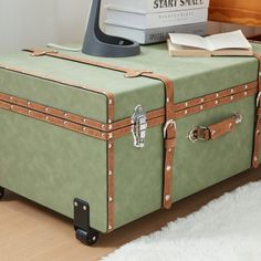 a green suitcase sitting on top of a white rug next to a computer monitor and book