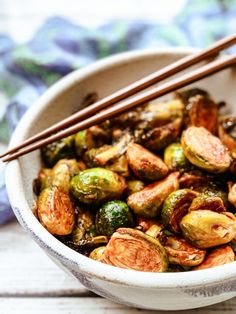 a bowl filled with brussel sprouts and chopsticks next to it