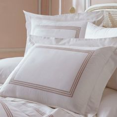 a bed with white sheets and pillows on top of it